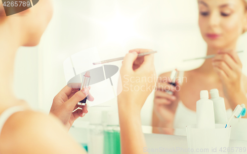 Image of woman with lipstick and make up brush at bathroom