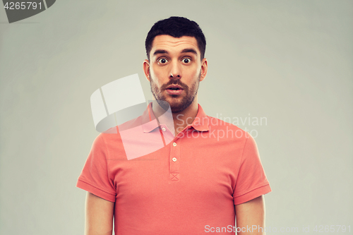 Image of surprised man in polo t-shirt over gray background