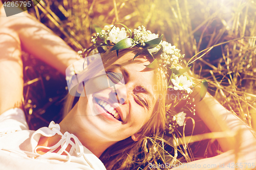 Image of happy woman in wreath of flowers lying on straw