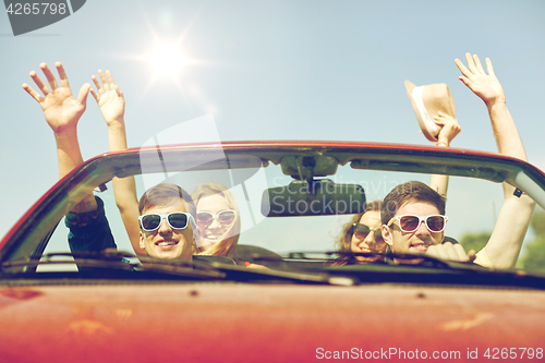 Image of happy friends driving in cabriolet car at country