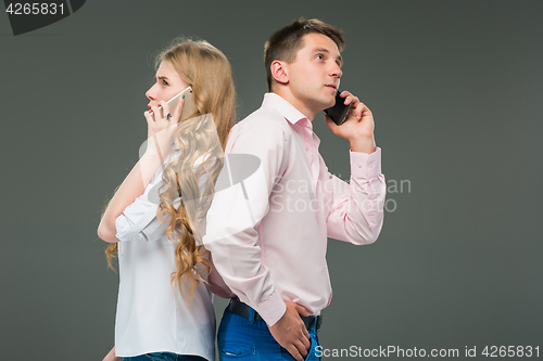 Image of Business concept. The two young colleagues holding mobile phones on gray background