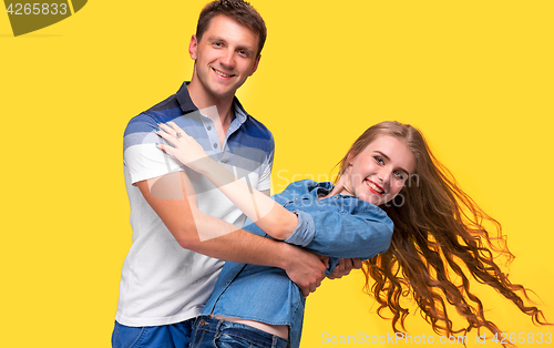 Image of Portrait of a young couple standing against yellow background
