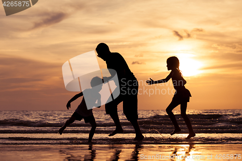 Image of Father and children playing on the beach at the sunset time.