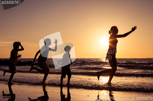 Image of Mother and children playing on the beach at the sunset time.