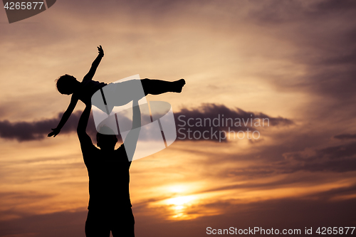 Image of Father and son playing on the beach at the sunset time.