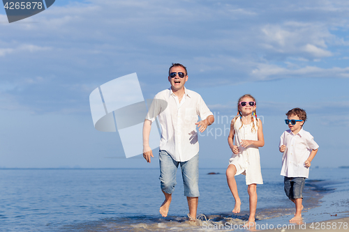 Image of Father and children playing on the beach at the day time.