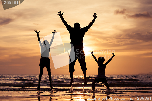 Image of Father and children playing on the beach at the sunset time.