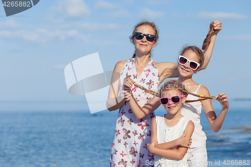 Image of Mother and children playing on the beach at the day time.