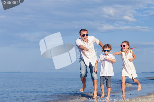 Image of Father and children playing on the beach at the day time.