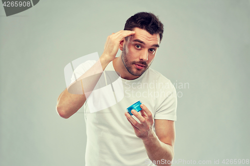 Image of happy young man styling his hair with wax or gel