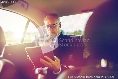 Image of senior businessman with tablet pc driving in car