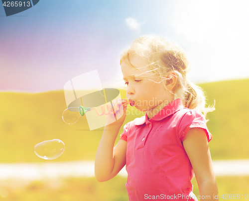 Image of little girl blowing soap bubbles outdoors