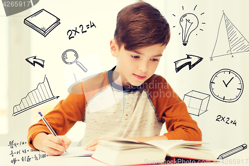 Image of student boy with book writing to notebook at home