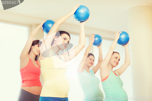 Image of happy pregnant women exercising with ball in gym
