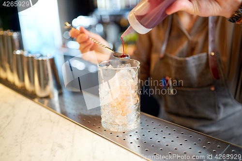 Image of bartender with cocktail stirrer and glass at bar