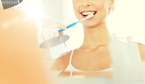 Image of woman with toothbrush cleaning teeth at bathroom