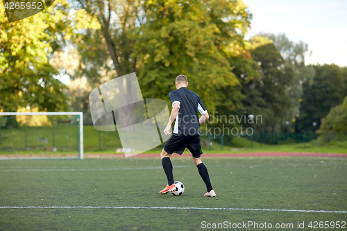 Image of soccer player playing with ball on football field