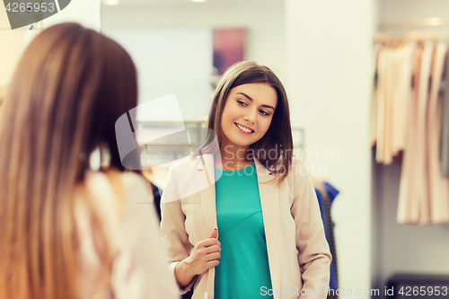 Image of happy woman posing at mirror in clothing store