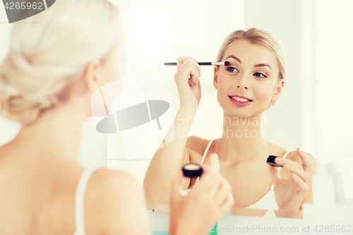 Image of woman with makeup brush and eyeshade at bathroom