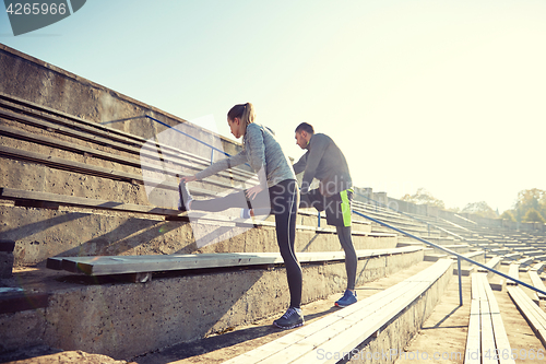 Image of couple stretching leg on stands of stadium