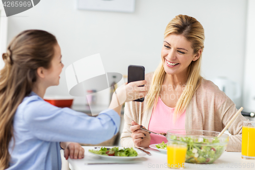 Image of happy family with smartphone having dinner at home