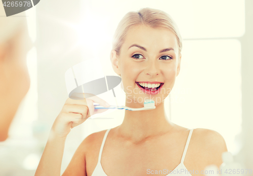 Image of woman with toothbrush cleaning teeth at bathroom