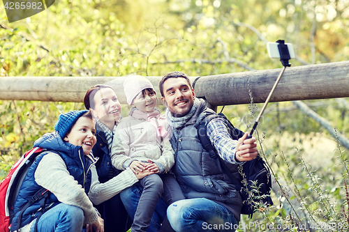 Image of happy family with smartphone selfie stick in woods