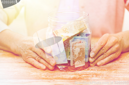 Image of close up of senior woman with money in glass jar