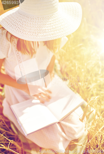 Image of close up of woman reading book on cereal field