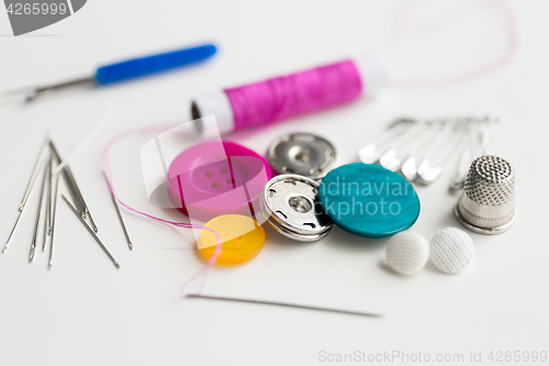 Image of sewing buttons, needles, pins and thread spool