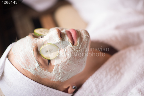 Image of woman is getting facial clay mask at spa