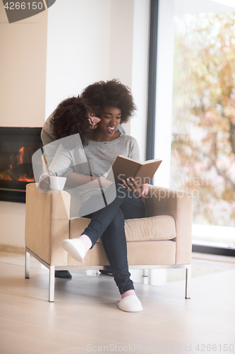 Image of multiethnic couple hugging in front of fireplace