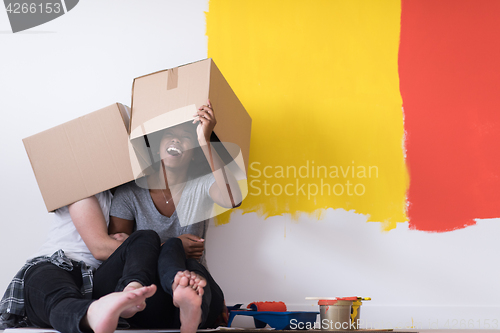 Image of young multiethnic couple playing with cardboard boxes