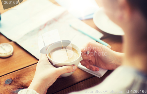 Image of close up of hands with coffee cup and travel stuff