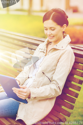 Image of woman with tablet pc sitting on bench in park