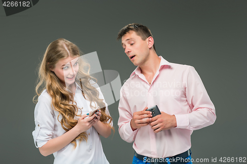 Image of Business concept. The two young colleagues holding mobile phones on gray background