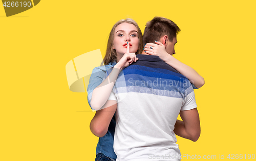 Image of Portrait of a young couple standing against yellow background