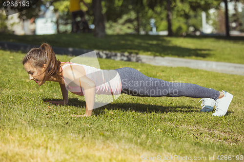 Image of Fit fitness woman doing stretching exercises outdoors at park