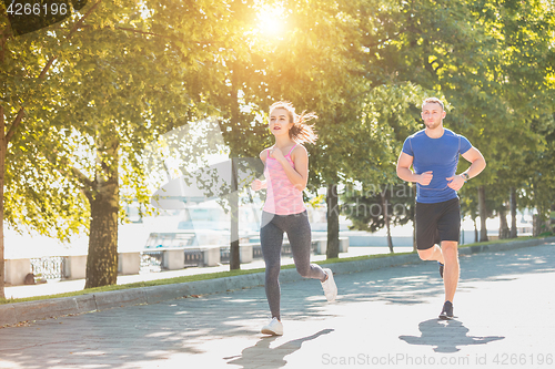 Image of The sporty woman and man jogging at park in sunrise light