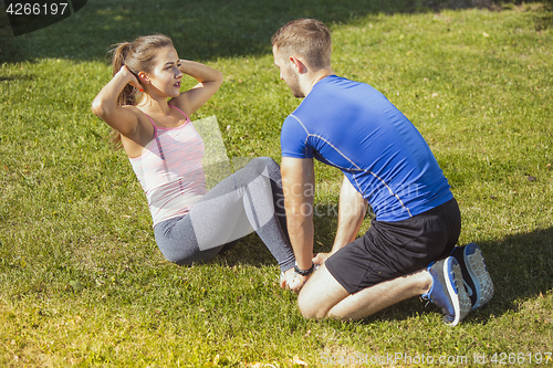 Image of Fit fitness woman and man doing stretching exercises outdoors at park