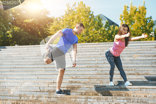 Image of Fit fitness woman and man doing stretching exercises outdoors at park