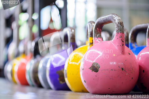 Image of colorful kettlebells in a row in a gym