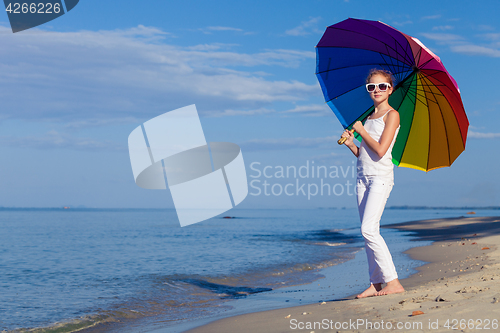 Image of Ten girl with umbrella standing on the beach