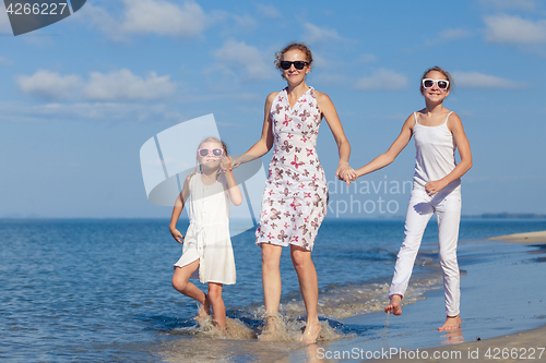 Image of Mother and children playing on the beach at the day time.