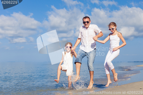 Image of Father and children playing on the beach at the day time.