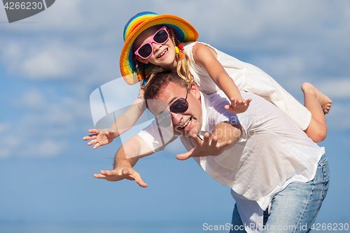 Image of Father and daughter playing on the beach at the day time.