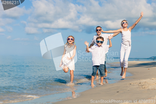 Image of Father and children playing on the beach at the day time.