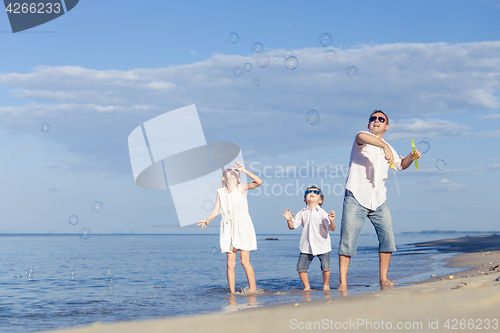 Image of Father and children playing on the beach at the day time.