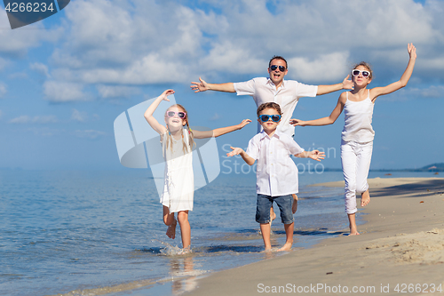 Image of Father and children playing on the beach at the day time.