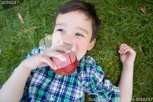 Image of Mixed Race Chinese and Caucasian Young Boy With Apple Relaxing O